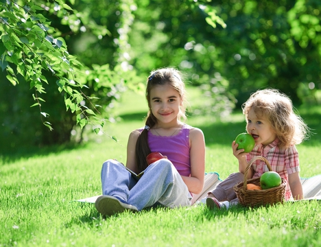 Two girls eating apples at the park.